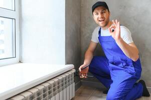 Repair heating radiator close-up. man repairing radiator with wrench. Removing air from the radiator photo