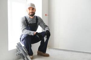 Man removes holes and bumps on the wall with a spatula and plaster photo