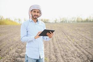 Young indian farmer standing at green turmeric agriculture field photo