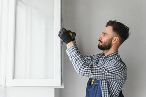 Worker in installing white plastic upvc window on house. photo