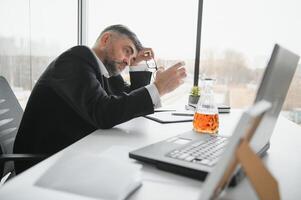 Old businessman drinking from stress. photo