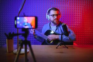 vlogger using smartphone to film podcast in studio. blogger with mobile phone, microphone and headphones filming video for social media broadcasting career. photo