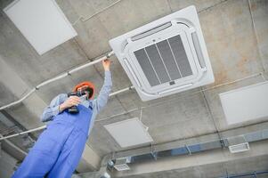 Happy Male Technician Repairing Air Conditioner. photo