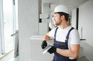 Portrait of a young foreman in uniform standing on a construction site indoors near a stepladder. photo