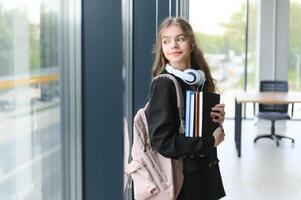 retrato de un Chica de escuela a escuela. ella sostiene libros en su manos. educación concepto. foto