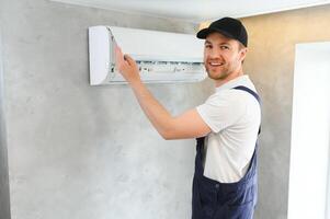 Happy Male Technician Repairing Air Conditioner. photo