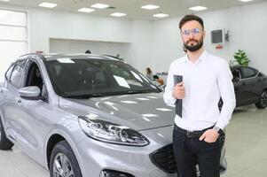 sonriente, simpático coche vendedor en pie en coche salón. foto