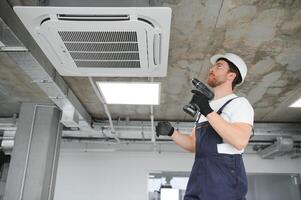 Happy Male Technician Repairing Air Conditioner photo