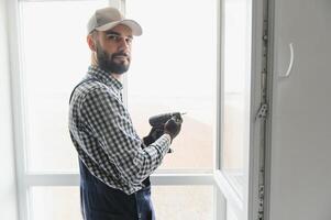 Worker in installing white plastic upvc window on house. photo