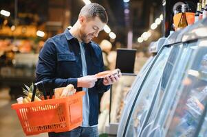 Portrait of smiling man walking with his trolley on aisle at supermarket. photo