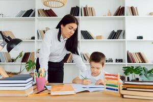 Portrait of handsome boy at workplace with his tutor sitting near by and telling something photo