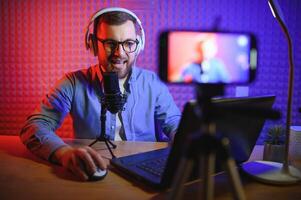 A video blogger records content in his studio. The host of the video blog is a young man who is very enthusiastic about telling his subscribers a story. photo