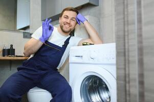 working man plumber repairs a washing machine photo