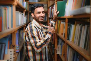 Happy smart indian or arabian guy, mixed race male, university student, in the library photo