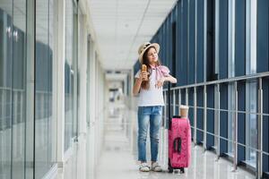 Little adorable kid in airport waiting for boarding indoors. Adorable little girl at airport eats fast food and drinks tea photo