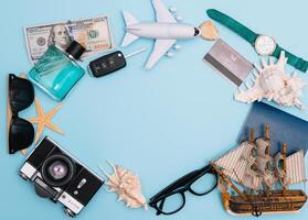 top view travel concept with retro camera films, smartphone, map, passport, compass and Outfit of traveler on blue background with copy space, Tourist essentials, vintage tone effect. photo