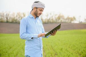 Portrait of young Indian Farmer wearing formal dress in green paddy field. photo