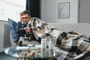 enfermo mayor hombre utilizando termómetro comprobación su temperatura sufrimiento desde estacional gripe o frío. foto