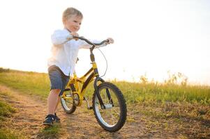 un hermoso chico con bicicleta en el verano campo. foto