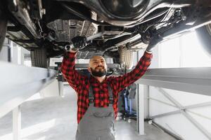 Mechanic working under car at the repair garage. Auto mechanic working in garage. Repair service. photo