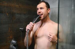 hermoso hombre canto mientras tomando ducha a hogar foto