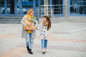 familia compras. madre y su hija son participación tienda de comestibles compras bolso con vegetales. foto