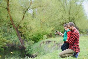 A father teaching his son how to fish on a river outside in summer sunshine photo