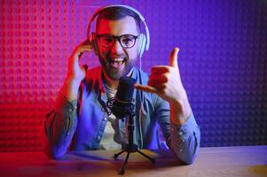 Young man recording or streaming podcast using microphone at his small broadcast studio. Content creator. photo