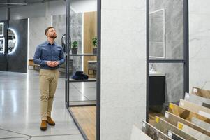 Middle age man choosing ceramic tiles and utensils for his home bathroom photo