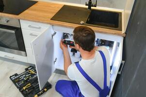 kitchen installation. Worker assembling furniture photo