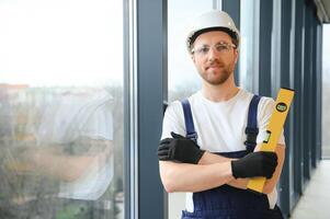 Worker using bubble level after plastic window installation indoors photo