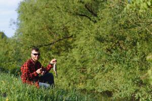 fisherman by the river with a catch of fish. Man fisherman holds in hand fish. photo