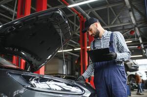 Examen mecánico debajo del capó del automóvil en el garaje de reparación foto