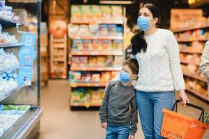 Mother and her son wearing protective face mask shop at a supermarket during the coronavirus epidemic. photo