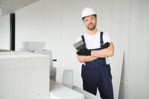 Portrait of positive, handsome young male builder in hard hat. photo