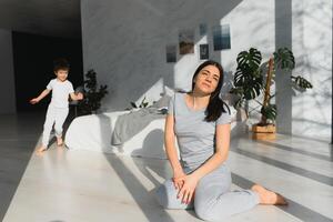 happy woman having fun with adorable son in pajamas in bedroom on mothers day. photo