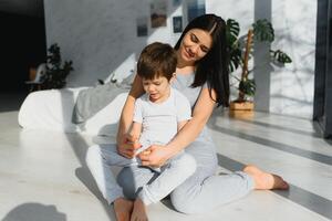 Mom is hugging her son sitting on the floor in the room. Family home shoot. photo