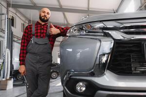 mecánico trabajando y participación llave inglesa de Servicio orden para mantener coche a el reparar tienda foto