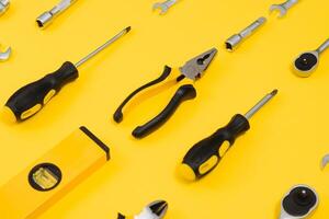 Yellow and black handy tools pilers and screwdriver isolated on yellow background. photo