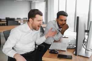 Two men traders sitting at desk at office together looking at data analysis discussing brainstorming successful strategy inspired teamwork concept close-up photo