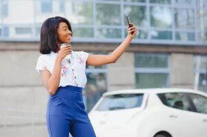 Good looking African female poses at camera of cell phone, makes selfie or makes video call photo