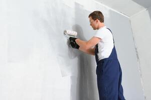 uno pintor con pintar rodillo haciendo pared principal revestimiento a hogar reparar renovación trabajar. foto