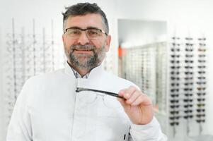 hermoso oftalmólogo participación los anteojos para un tratar afuera. optometrista ofrecimiento a vestir un par de lentes. imagen con pequeño profundidad de campo enfocado en el manos y lentes foto