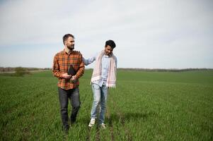 el concepto de internacional relaciones en agrario negocio. indio y europeo agricultores estar en un campo de verde trigo foto