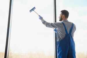 Young man cleaning window in office photo