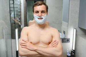 Confident guy using shaver in bathroom photo