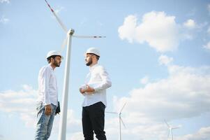 A team of male engineers working together at wind turbine generator farm. photo