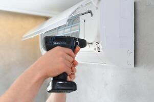 specialist cleans and repairs the wall air conditioner photo