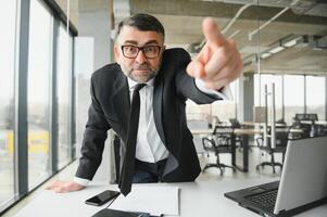 enojado empresario sentado a el mesa y gritando encima. foto