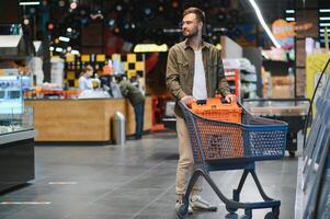 Handsome young man choosing food in the supermarket. photo